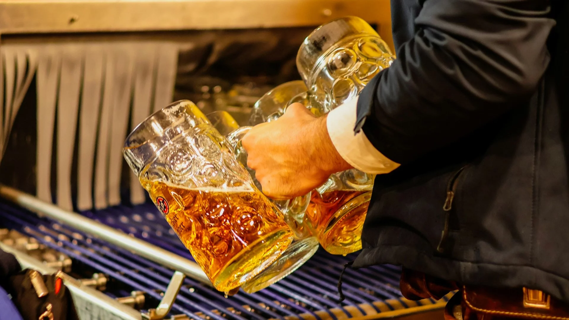 Ceny piwa w Niemczech rosną. Osoba trzymająca w dłoniach kufle z piwem. Ceny piwa w Niemczech rosną.