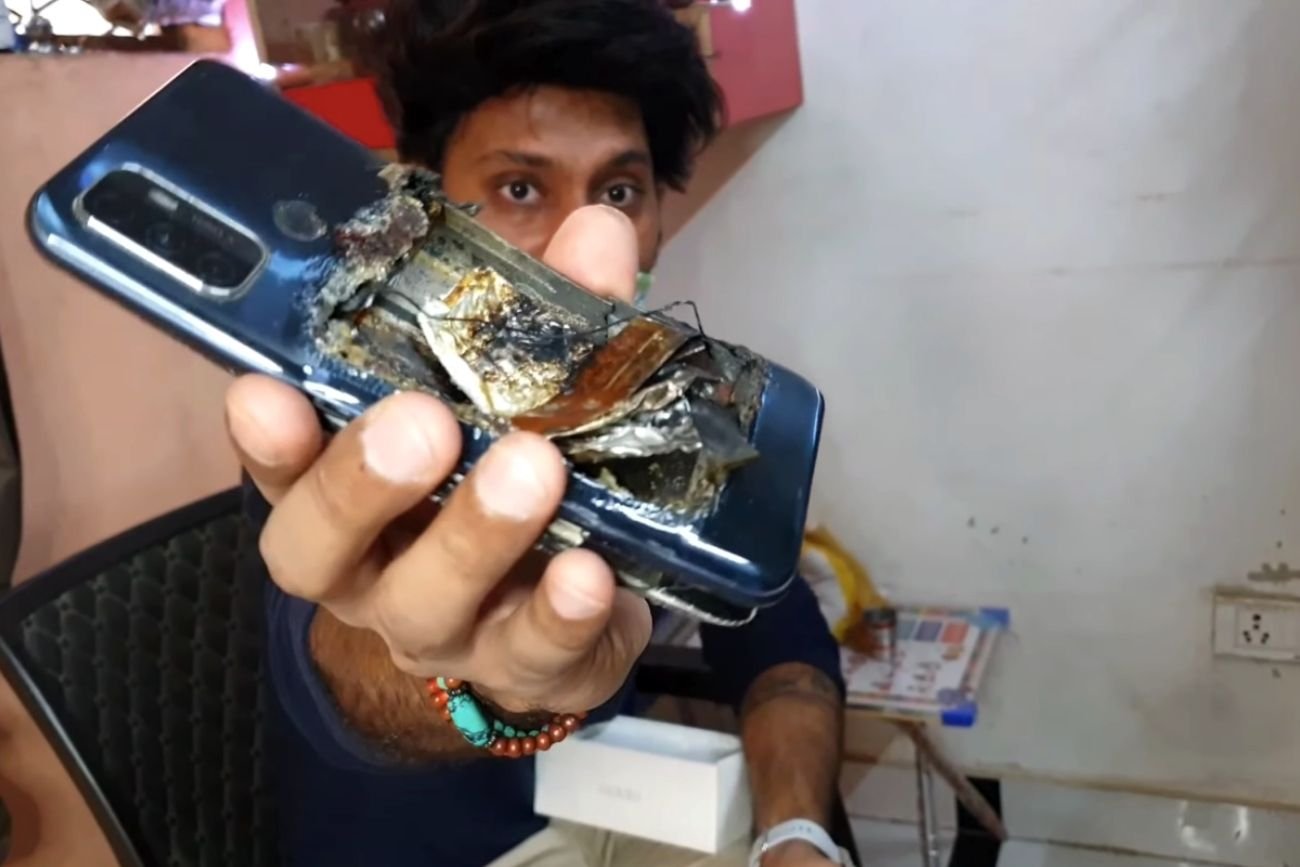 Indyjski mężczyzna pokazuje zepsuty telefon, który chwilę wcześniej wybuchł w kieszeni jego kolegi