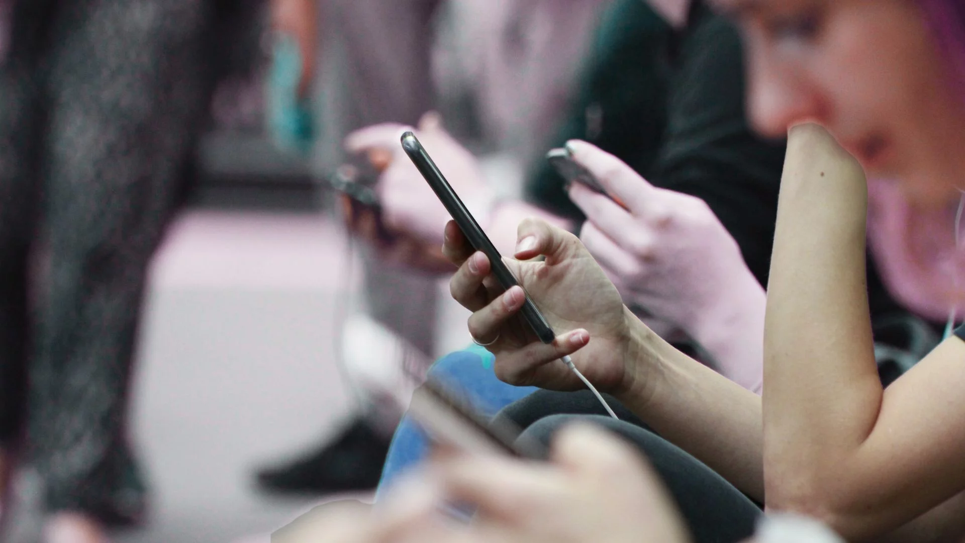 Osoby trzymają w rękach telefony.