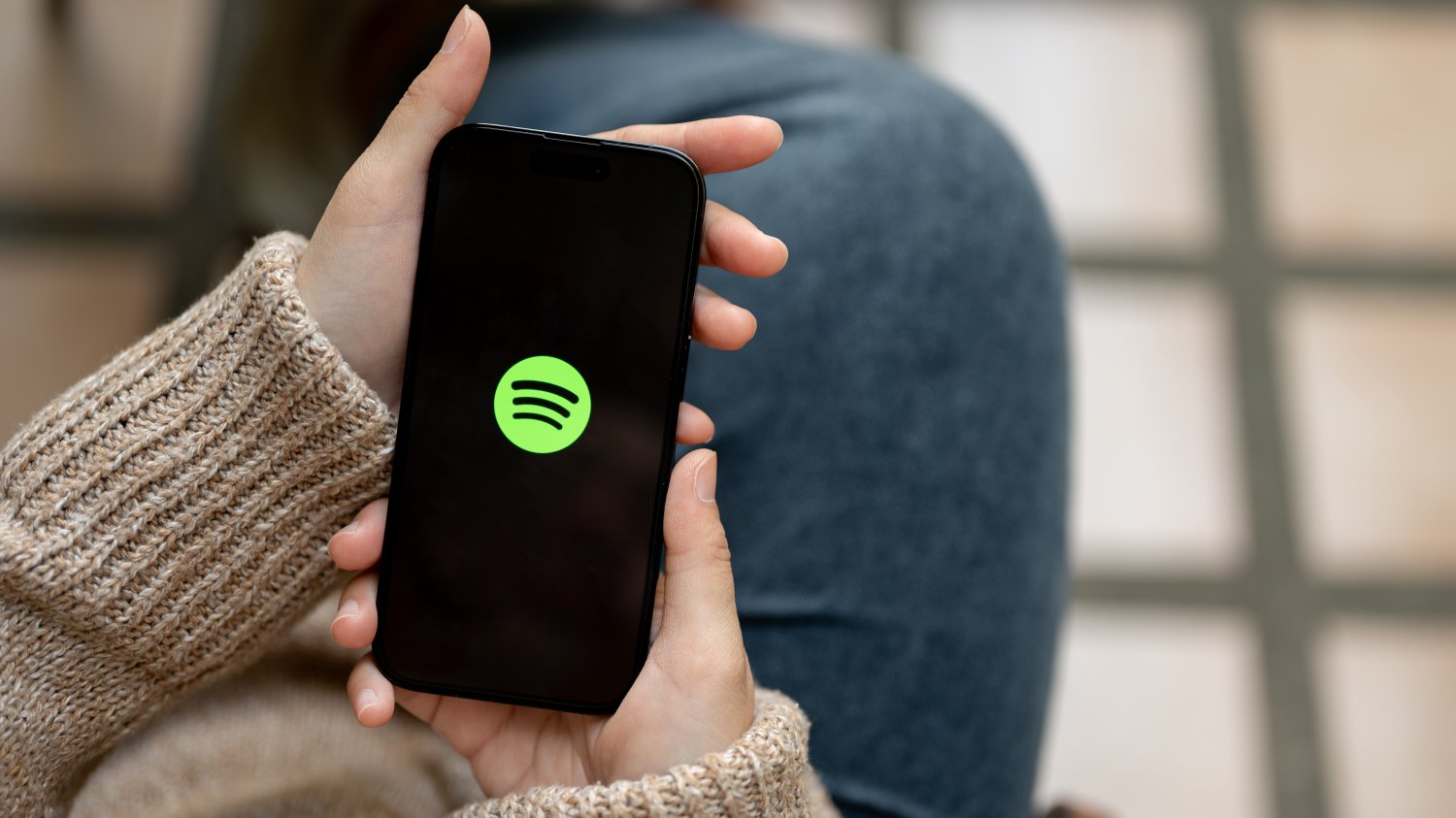 Zbliża się Spotify Wrapped 2025. Tegoroczne polskie listy przebojów mogą być dziwne Kobieta trzymająca smartfon z logiem Spotify. W tym roku Polacy wyjątkowo dużo słuchali muzyki od AI.