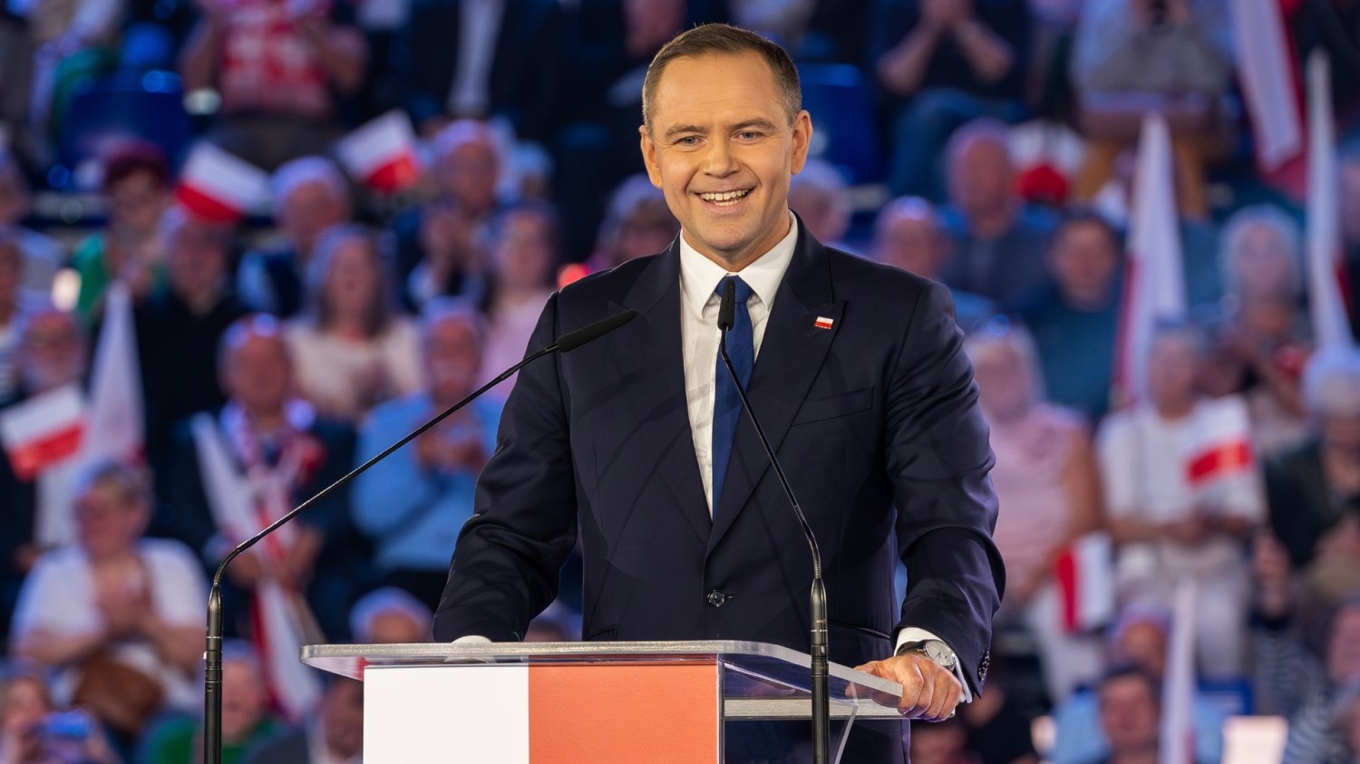 Uśmiechnięty Karol Nawrocki przemawia.