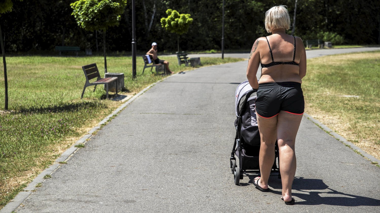 Lato, kobieta idzie chodnikiem w parku w stroju kąpielowym