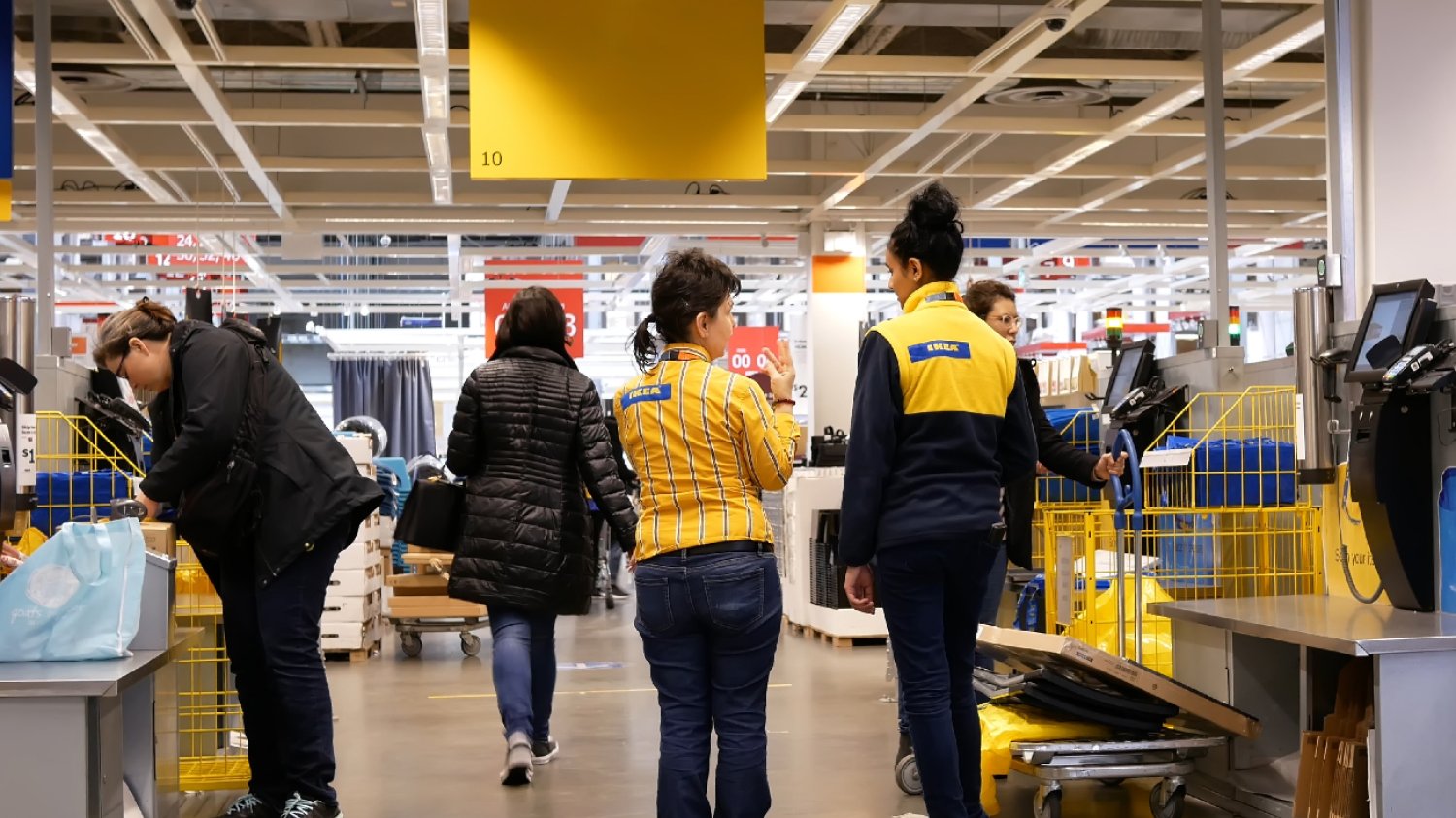 pracownicy IKEA w sklepie stacjonarnym doradzają klientom przy kasie samoobsługowej