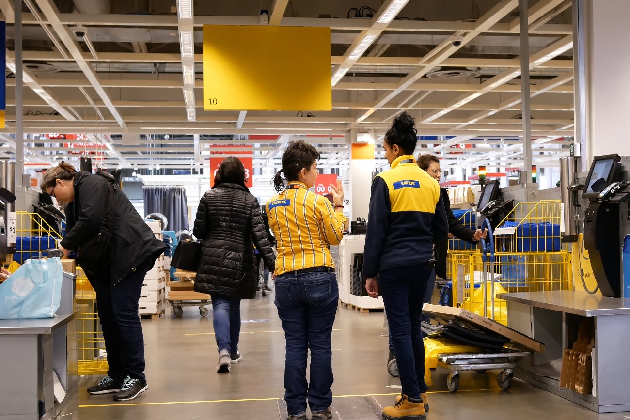 pracownicy IKEA w sklepie stacjonarnym doradzają klientom przy kasie samoobsługowej