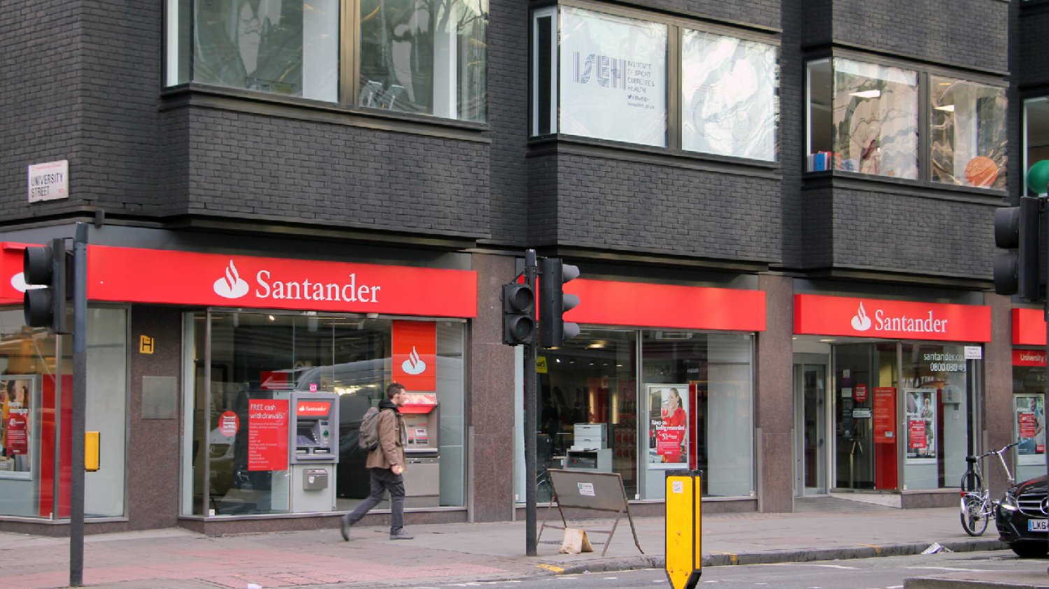 Przechodzień idący obok budynku Santander Bank