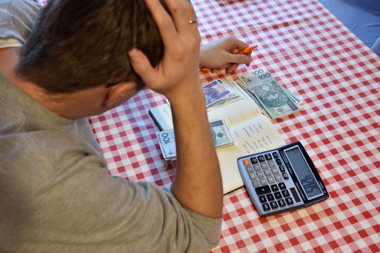 mężczyzna liczy pieniądze na rachunki przy stole