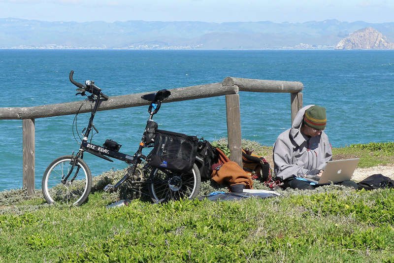 Turysta podczas podróży ładuje laptopa za pomocą przenośnych baterii słonecznych.