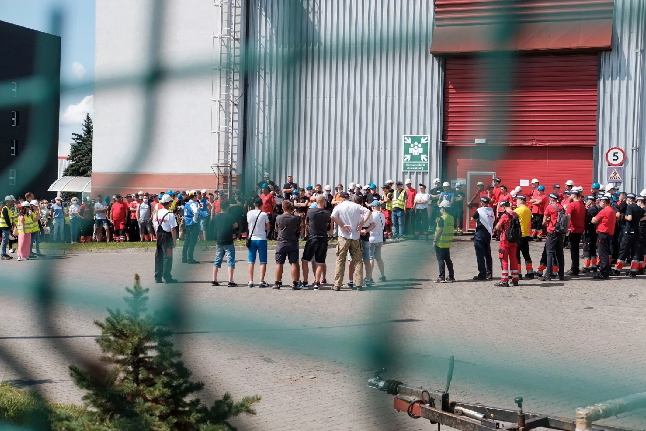 grupa mężczyzn ubrana w odzież roboczą podczas strajku za zieloną siatką