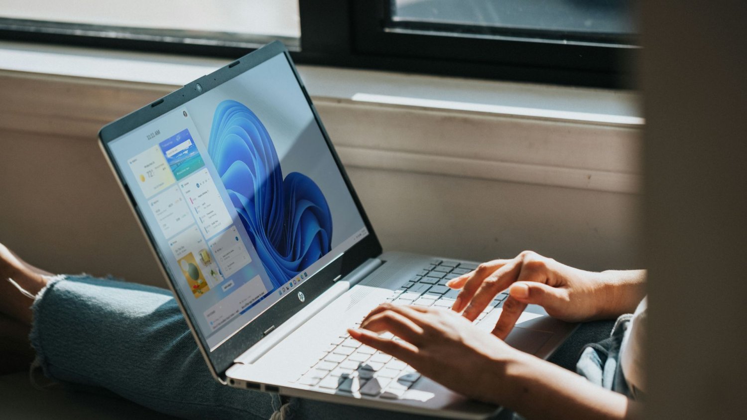 Kobiet pracuje na laptopie z Windows 11. Microsoft zaleca przesiadkę na ten system, dla Windows 10 kończy się wsparcie.