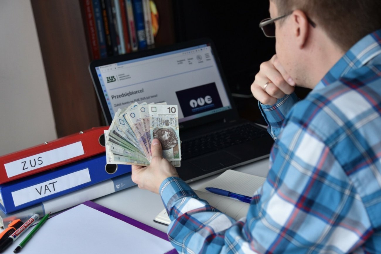 Mężczyzna, pieniądze polskie, komputer.