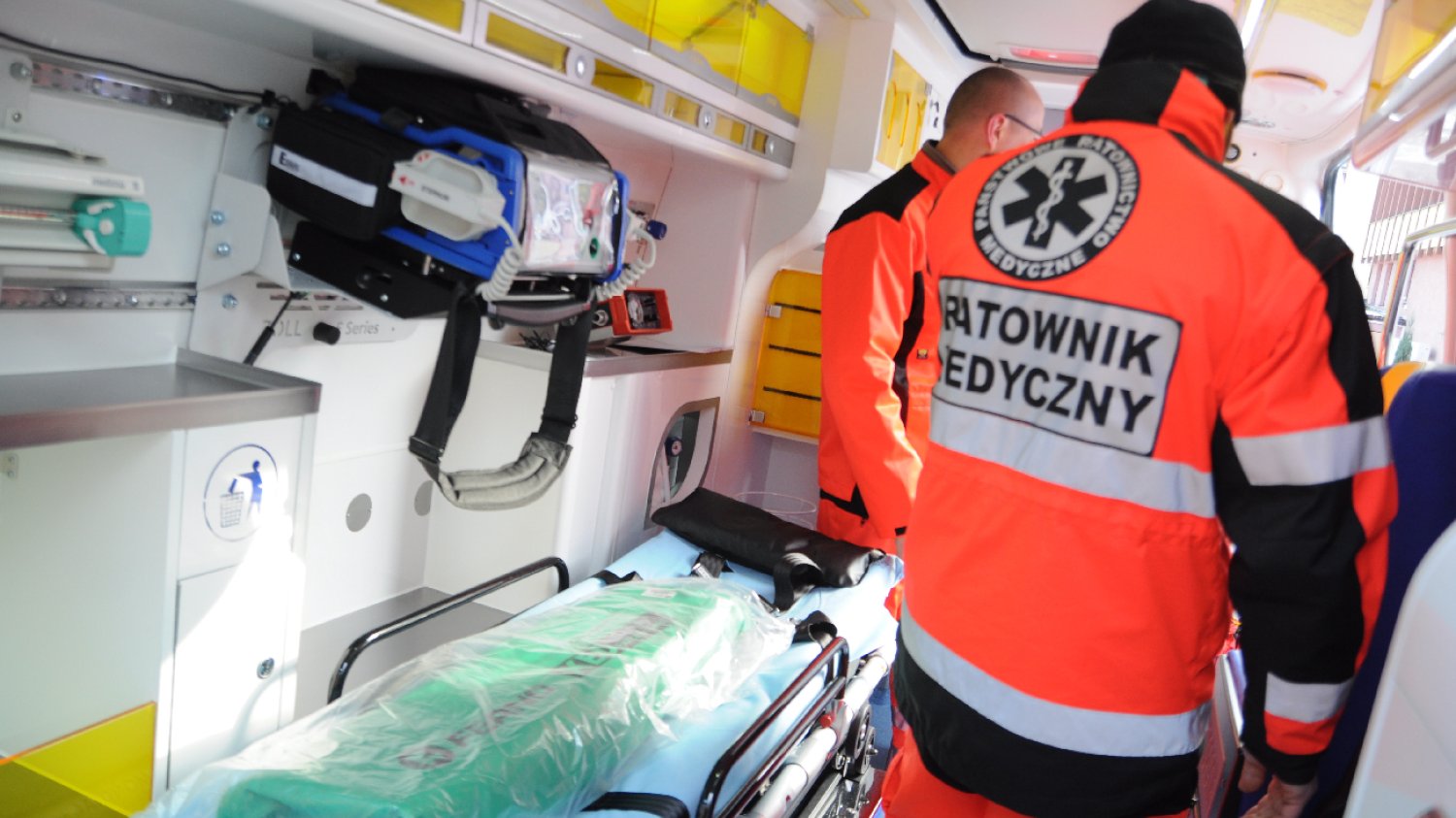 dwóch ratowników medycznych w karetce idzie po pacjenta