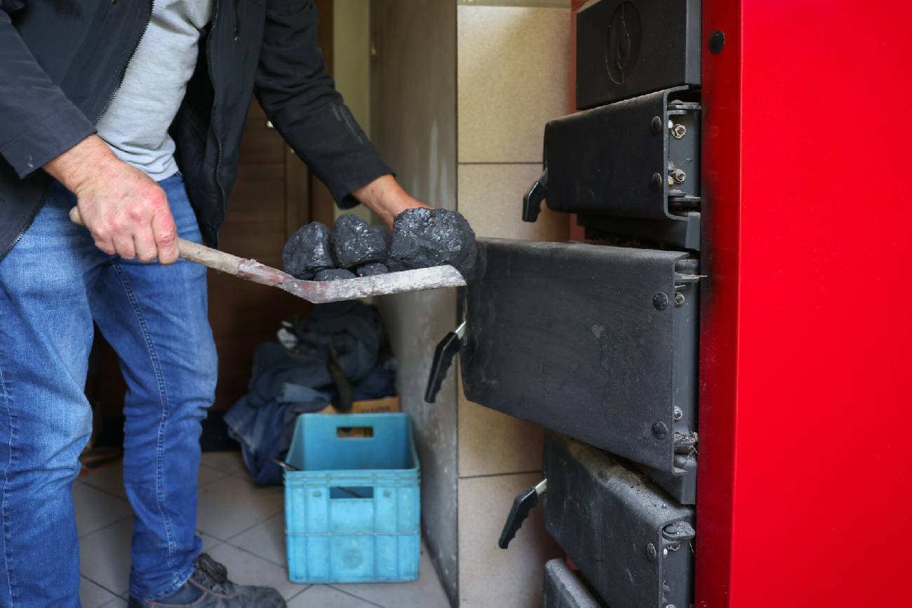 Mężczyzna palący w piecu węglem