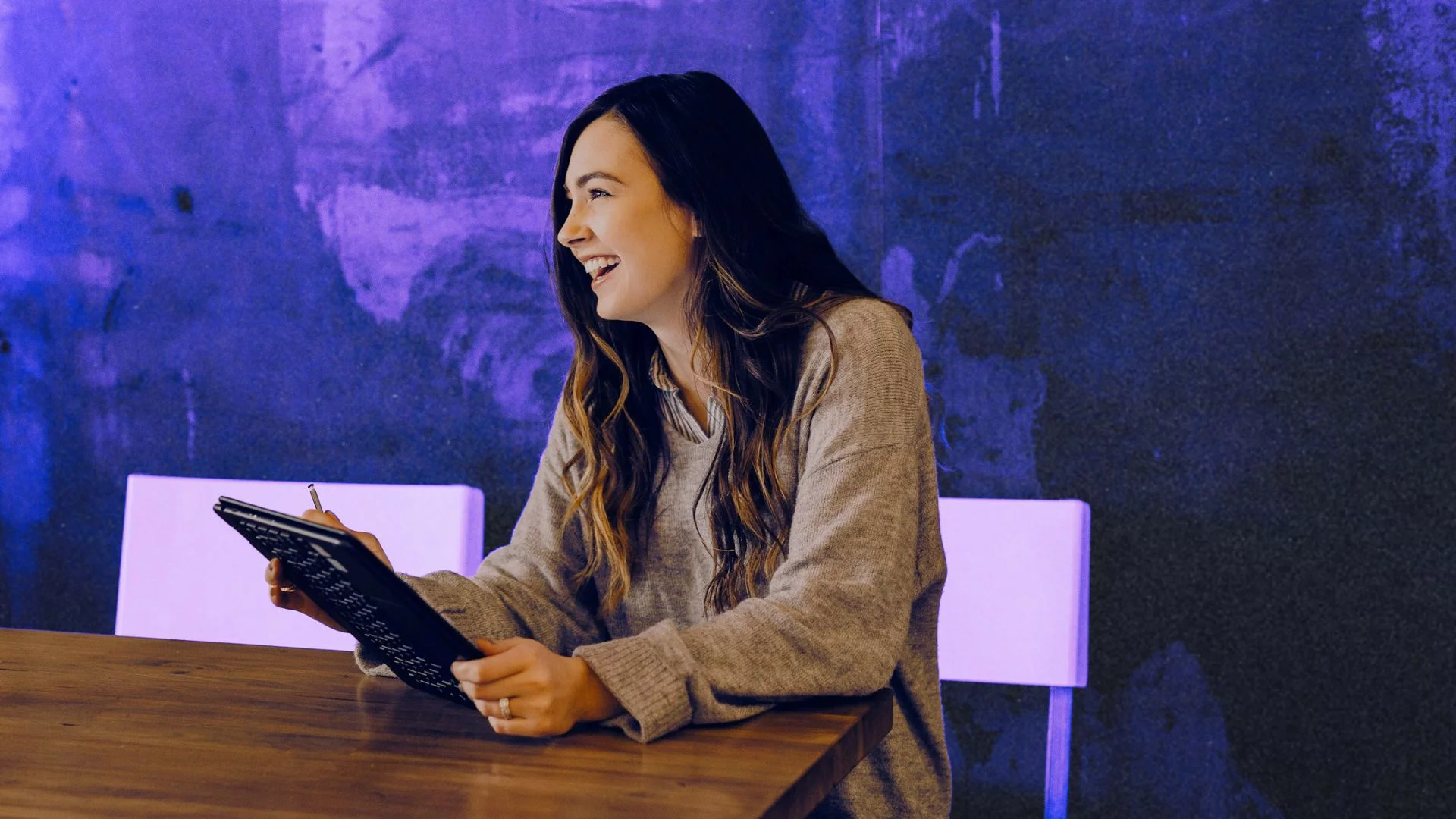 Kobieta śmiejąca się za biurkiem.