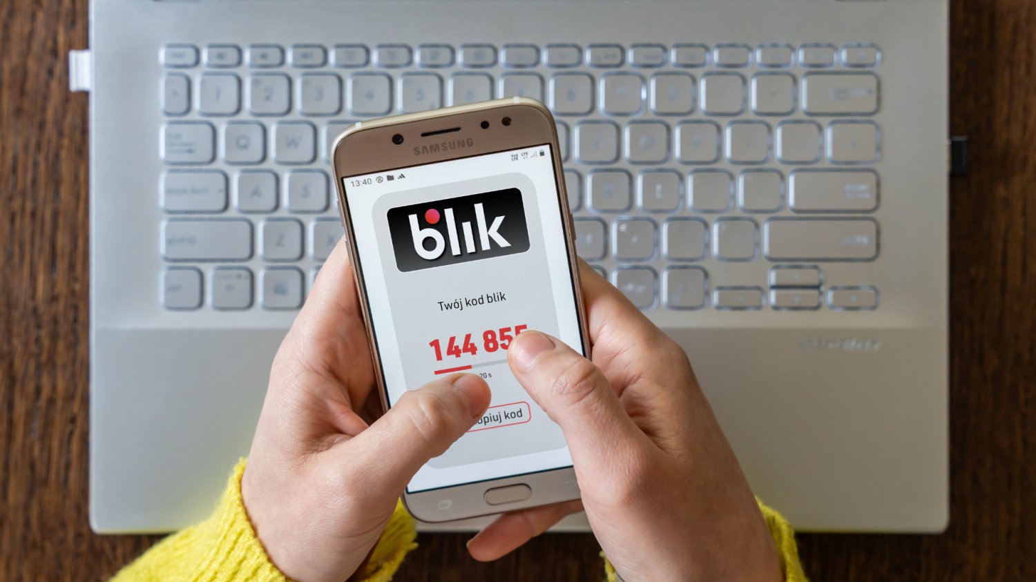 Polski BLIK może podbić Europę. UE szykuje przełom w płatnościach Ktoś płaci blikiem. Ktoś trzyma telefon z kodem BLIK i kupuje przez internet. W tle laptop.