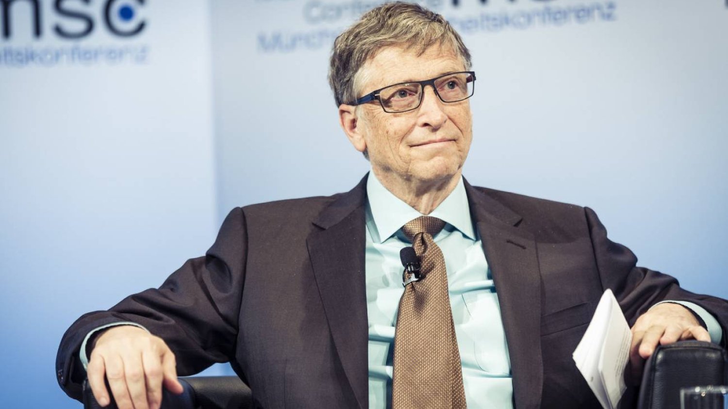 Bill Gates w garniturze podczas konferencji prasowej.