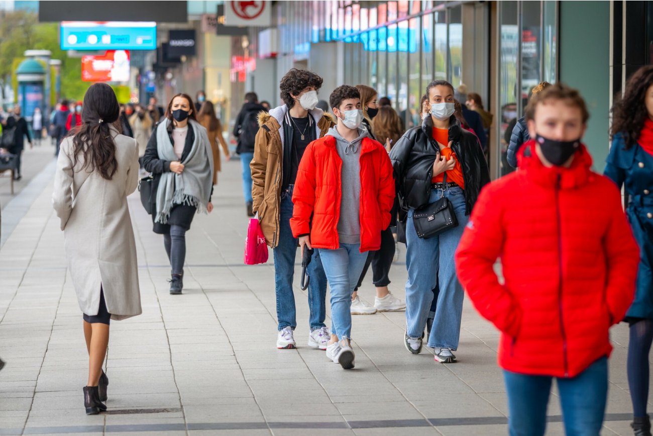 ludzie idą ulicą w centrum Warszawy w maseczkach na twarzy