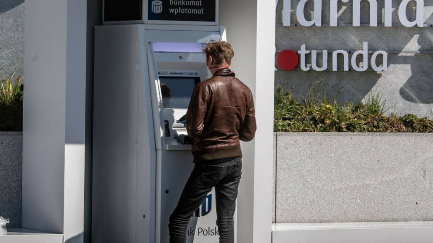 Mężczyzna przy bankomacie PKO BP