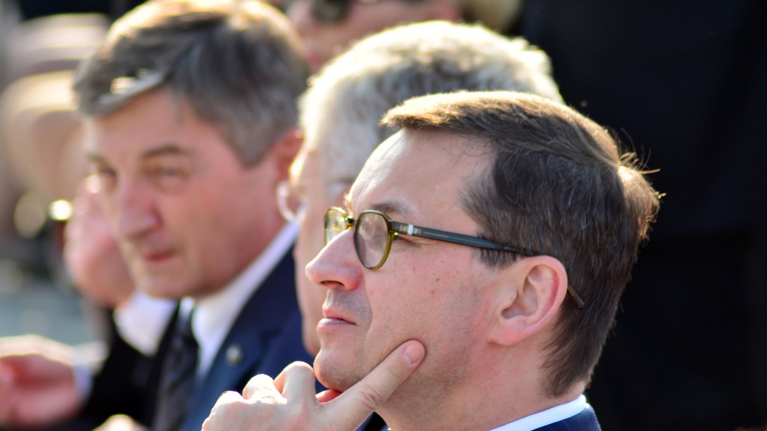 zamyślony Mateusz Morawiecki patrzy w górę