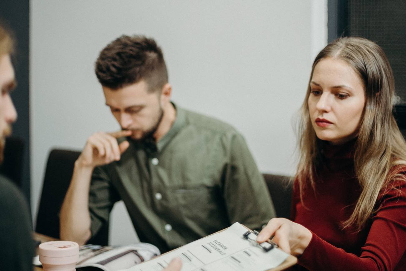 mężczyzna i kobieta na rozmowie kwalifikacyjnej, kobieta oddaje formularz