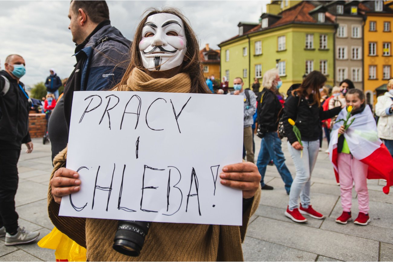 kobieta na strajku w Warszawie przy Kolumnie Zygmunta trzyma tabliczkę w napisem pracy i chleba