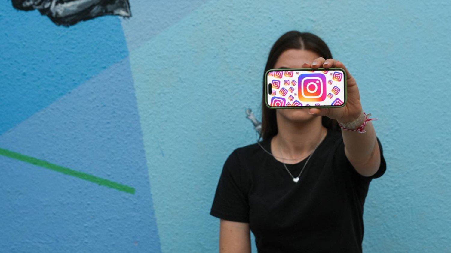 Kobieta trzymająca smartfon z logo Instagrama.