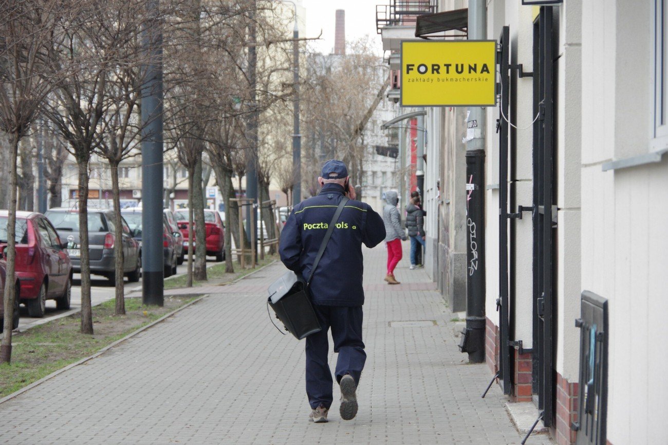 Listonosz idzie przez polskie miasteczko.