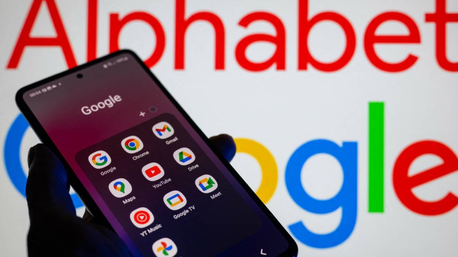 Dłoń trzymająca smartfon z apkami Google.