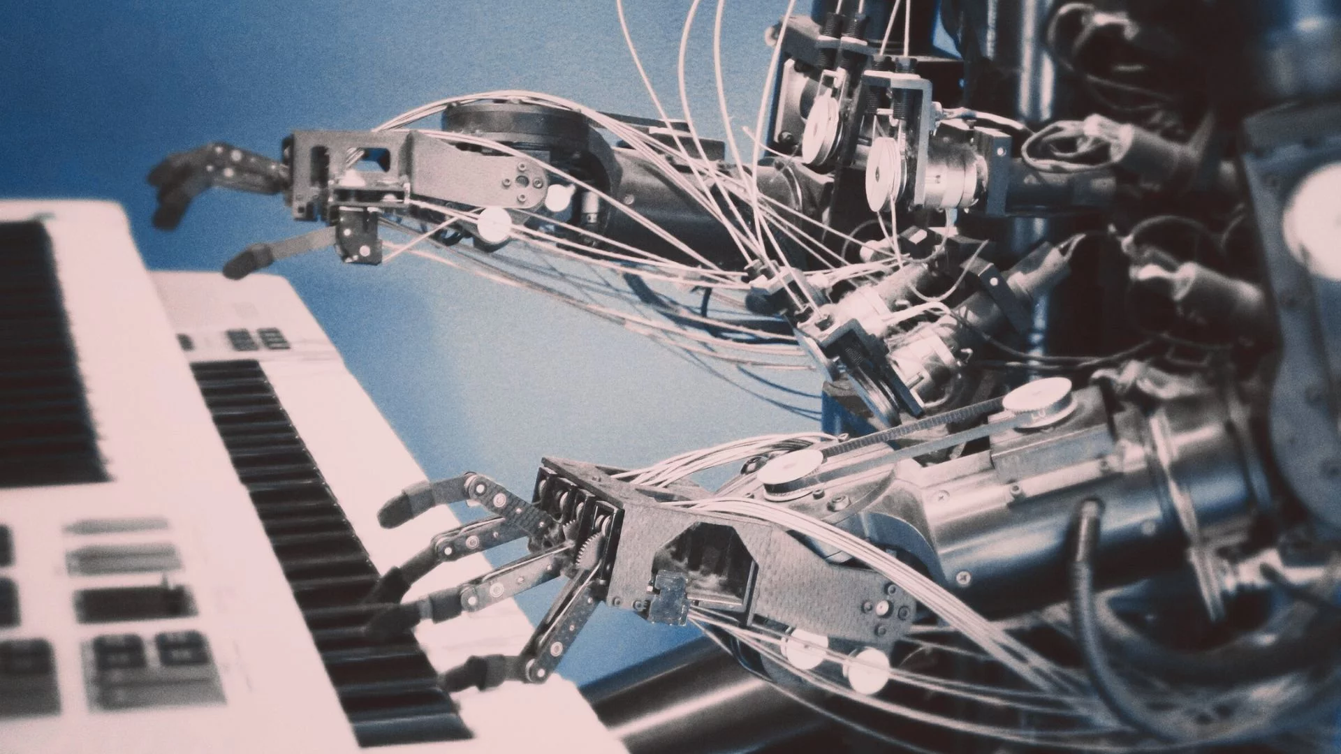 Robotyczne ręce grają na pianinie.