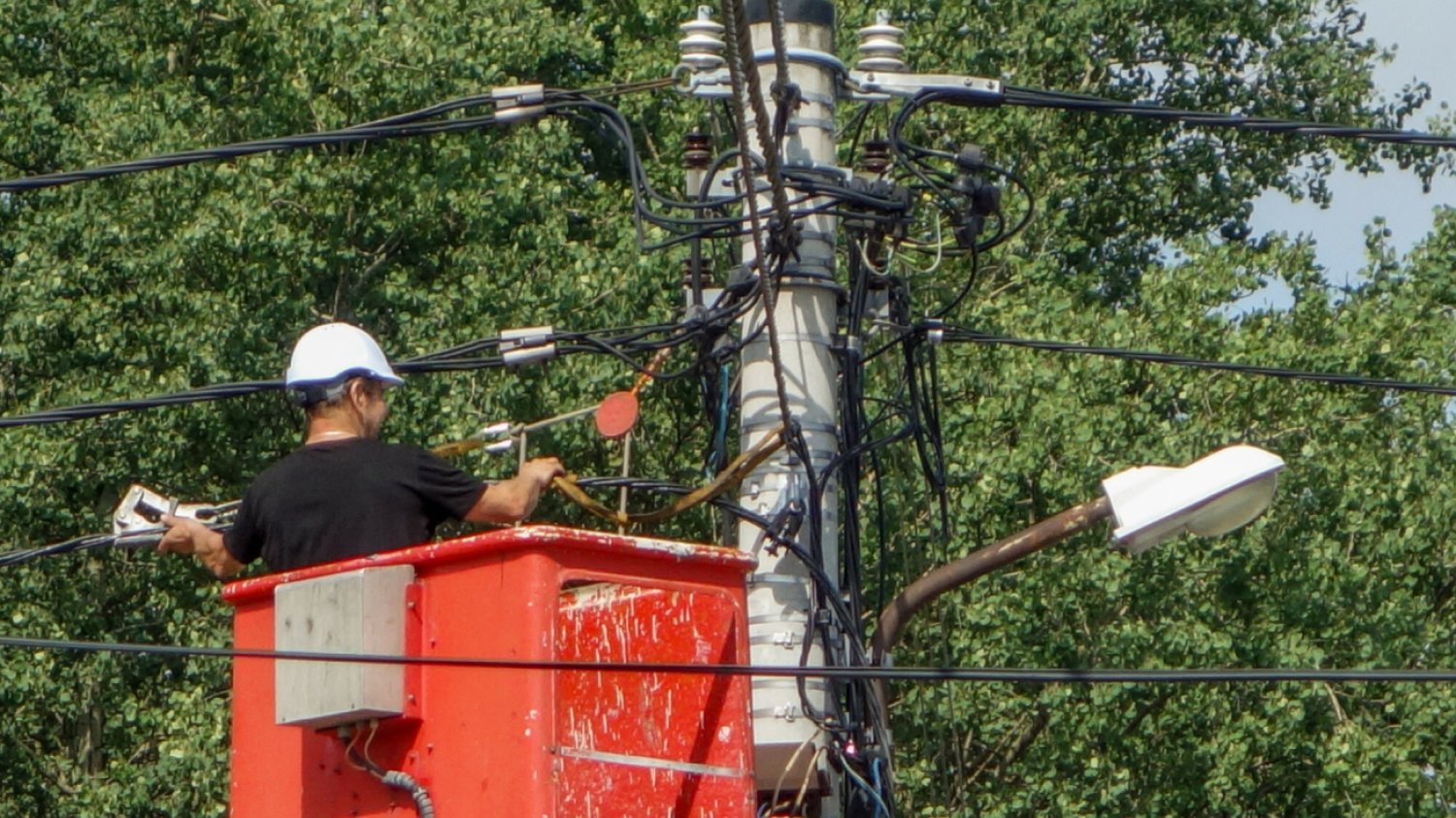 elektryk w kasku na czerwonym podnośniku