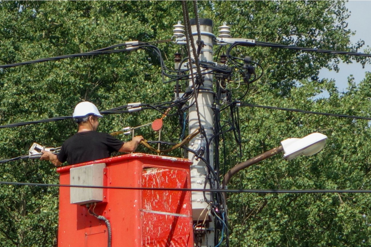 elektryk w kasku na czerwonym podnośniku