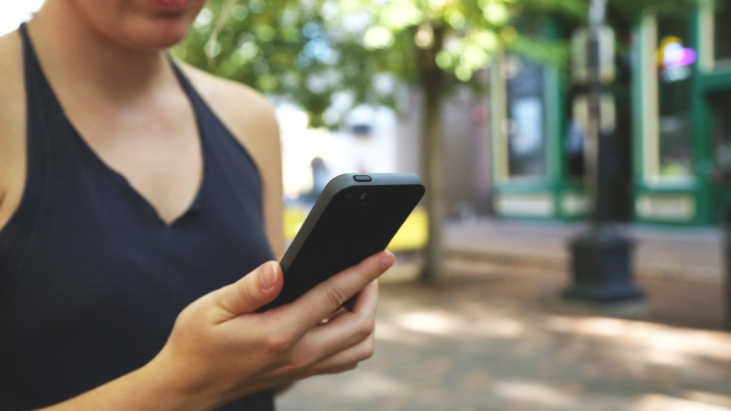 Kobieta spogląda na trzymany w ręku telefon