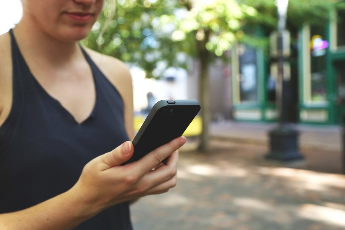 Kobieta spogląda na trzymany w ręku telefon