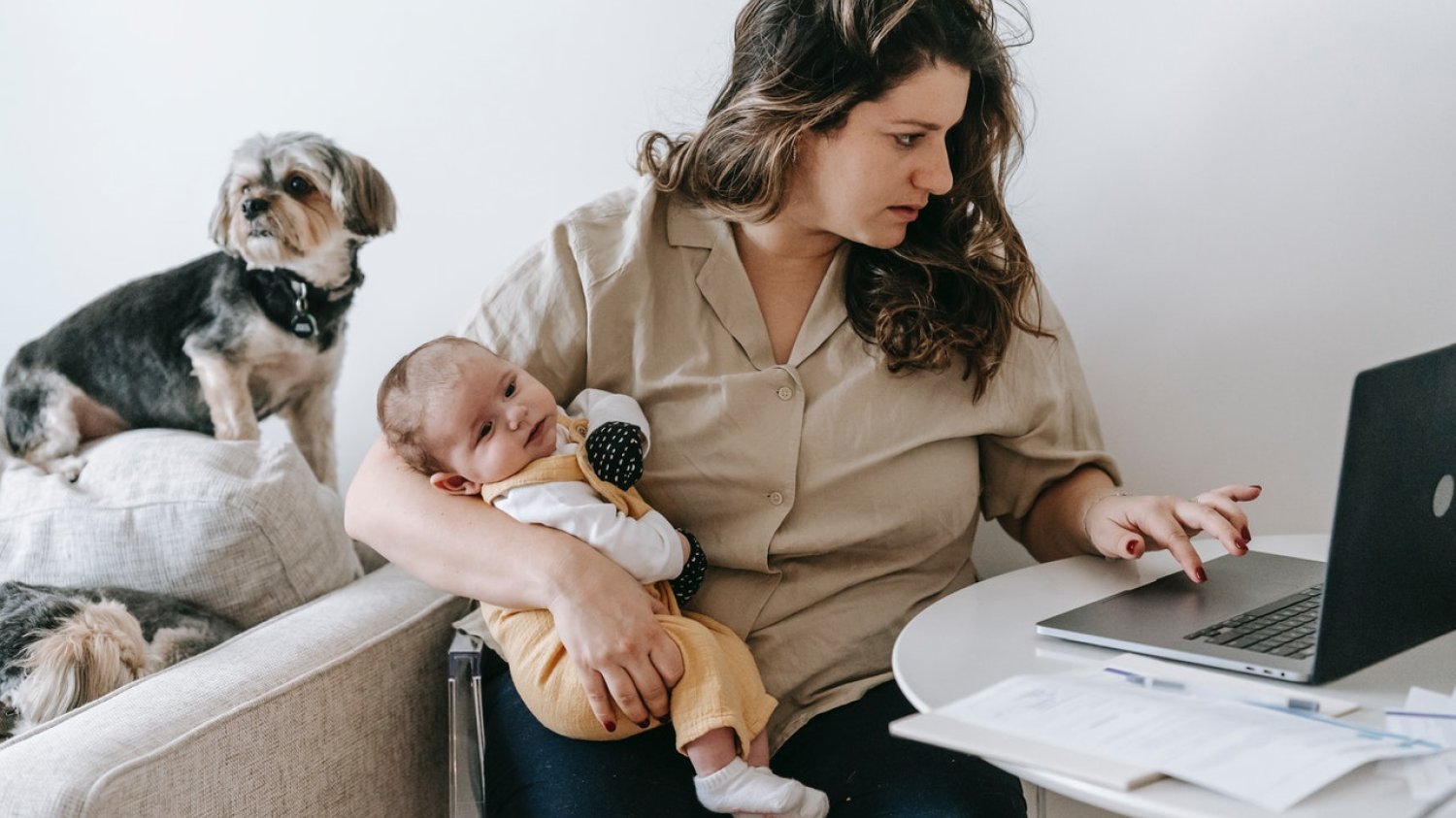 Home office - kobieta przy komputerze zajmuje się małym dzieckiem.