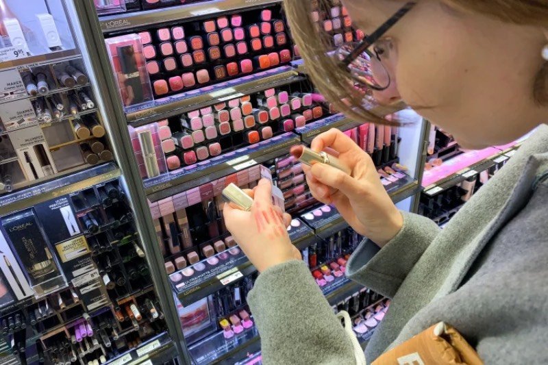 Kobieta wybierająca szminkę w drogerii.