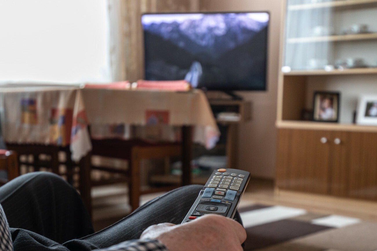 Mężczyzna z pilotem w ręku oglądający telewizję