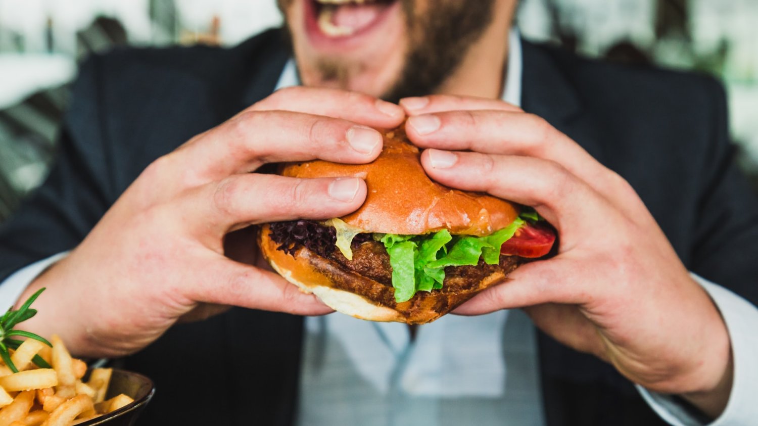 Mężczyzna w garniturze je hamburgera