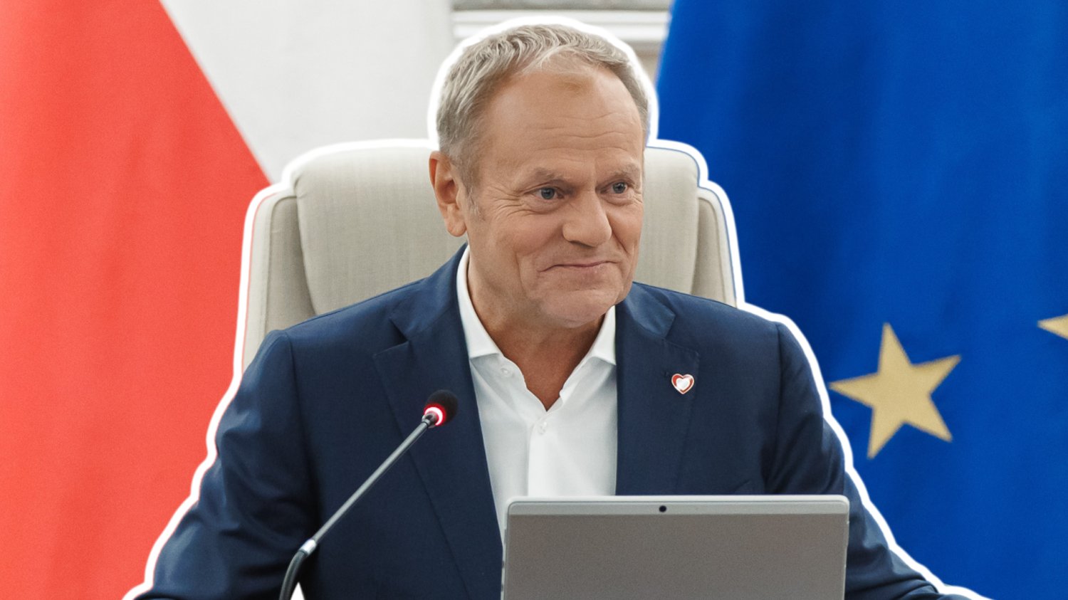 Donald Tusk na fotelu. W tle flaga Unii Europejskiej i Polski