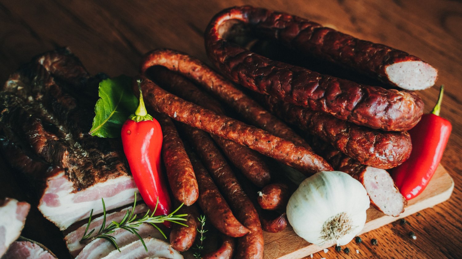Polska żywność podbija światowe rynki. Wiemy, które kraje kupują najwięcej Produkty mięsne na drewnianej desce. Kiełbasa, szynka.