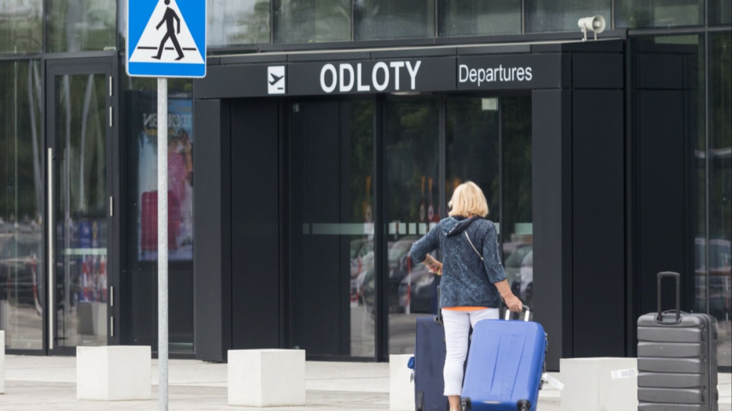 Turystyka z walizkami przed halą odlotów na lotnisku.