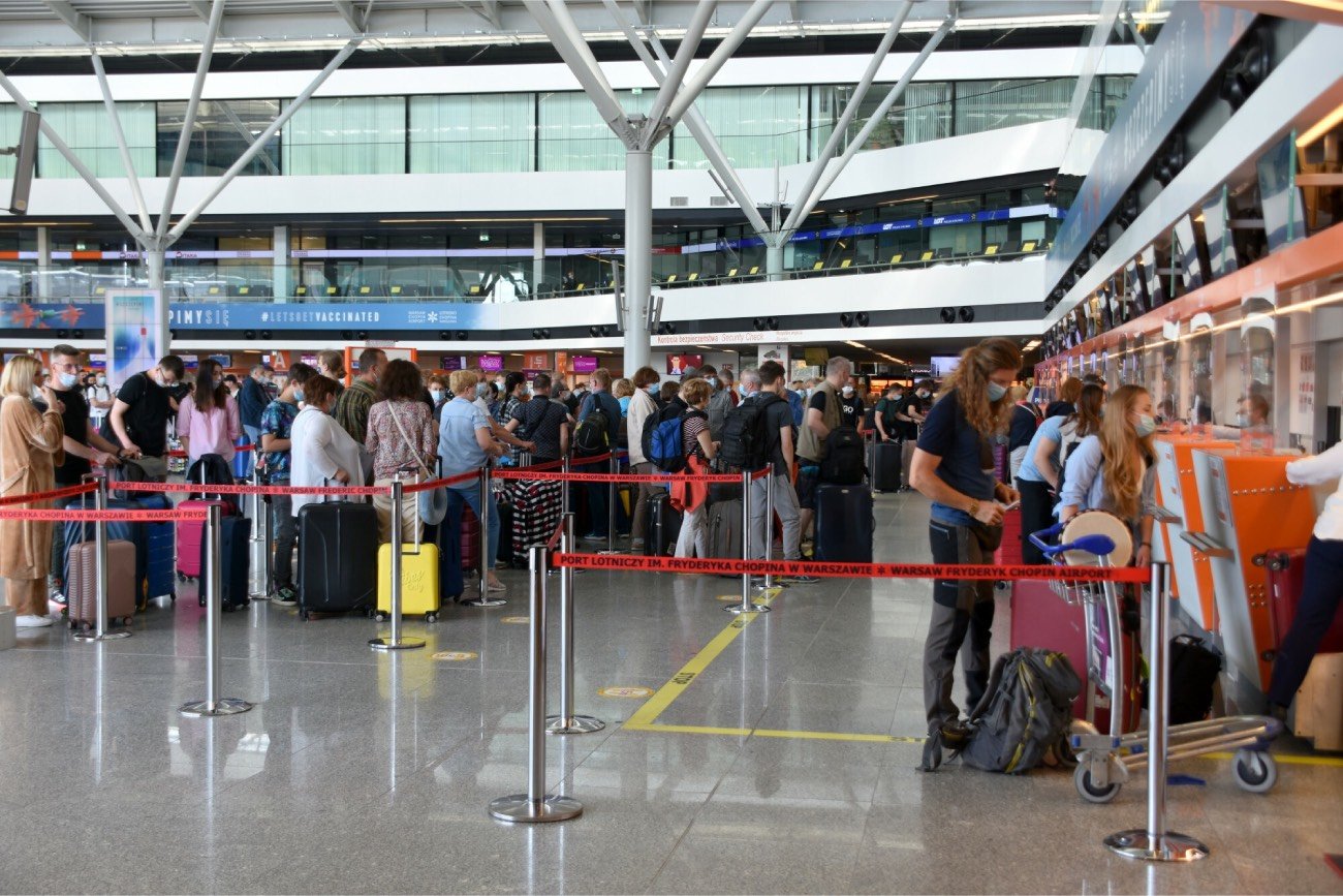 ludzie stojący w kolejce do odprawy na lotnisku Chopina w Warszawie
