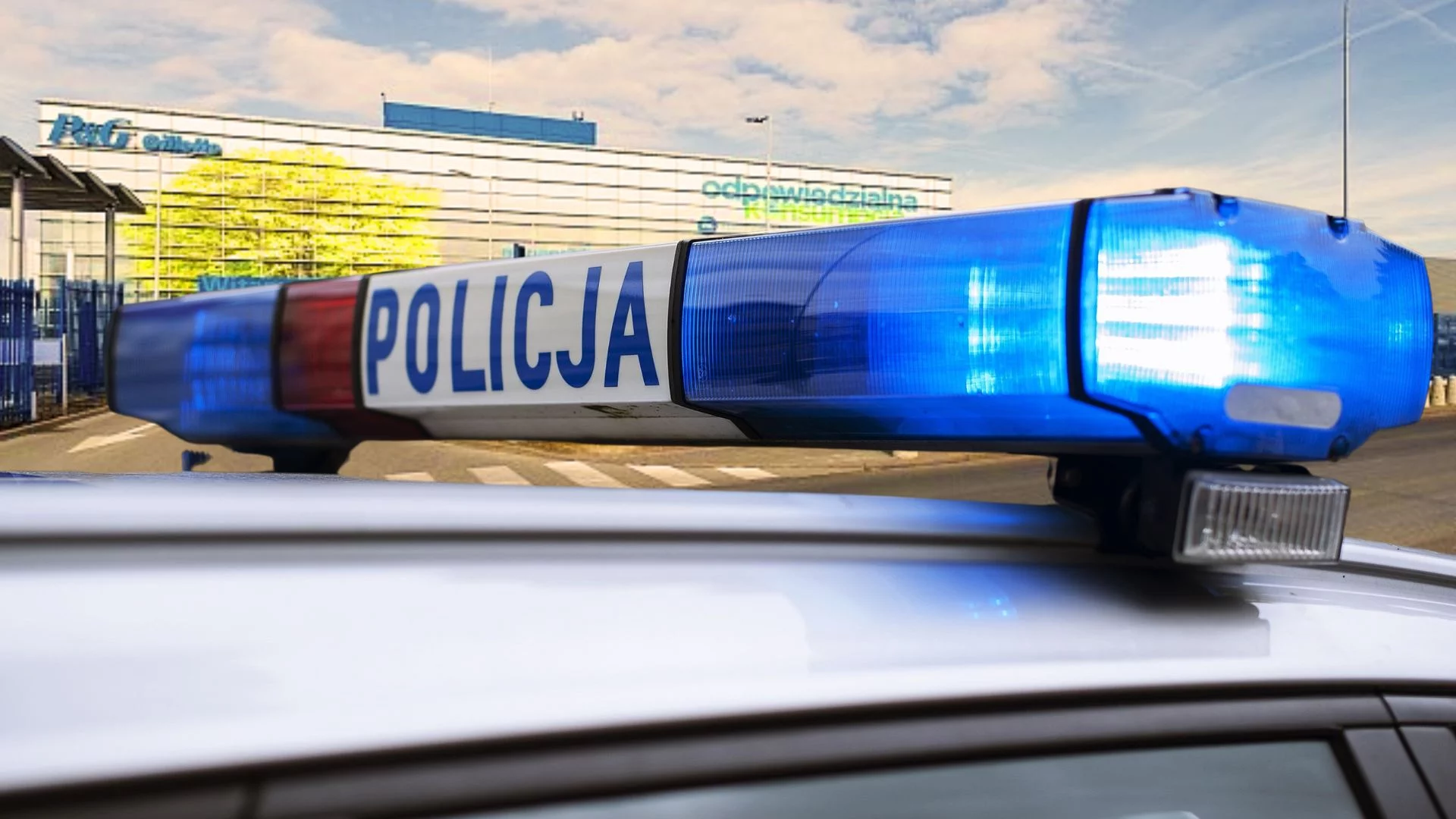 koguty na policyjnym radiowozie na tle łódzkiej fabryki Gilette