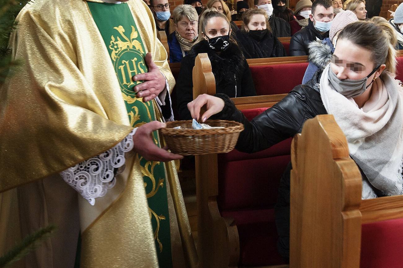 Ksiądz zbiera datki na tace podczas mszy