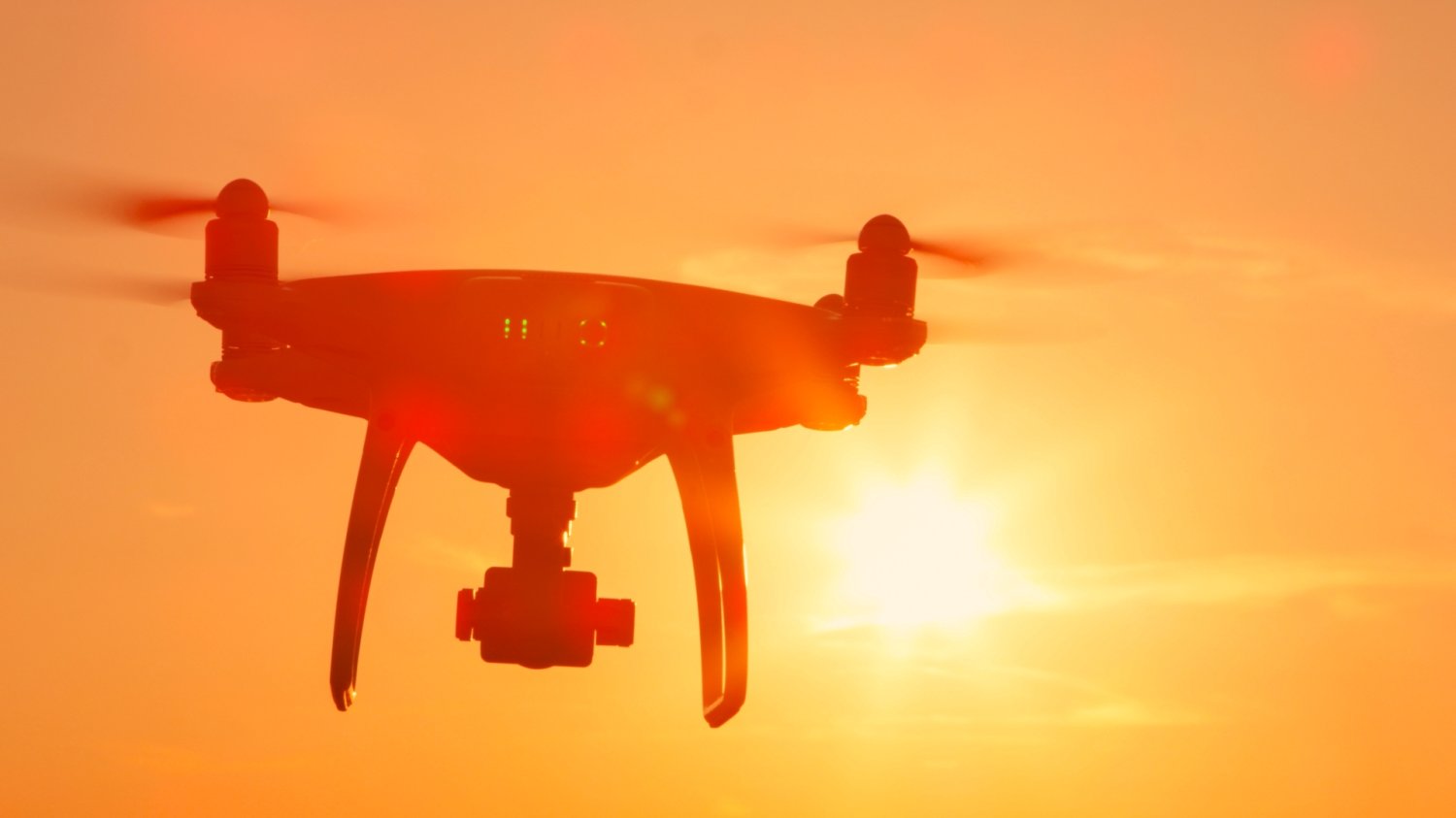 Dron w powietrzu na tle słonecznego nieba.