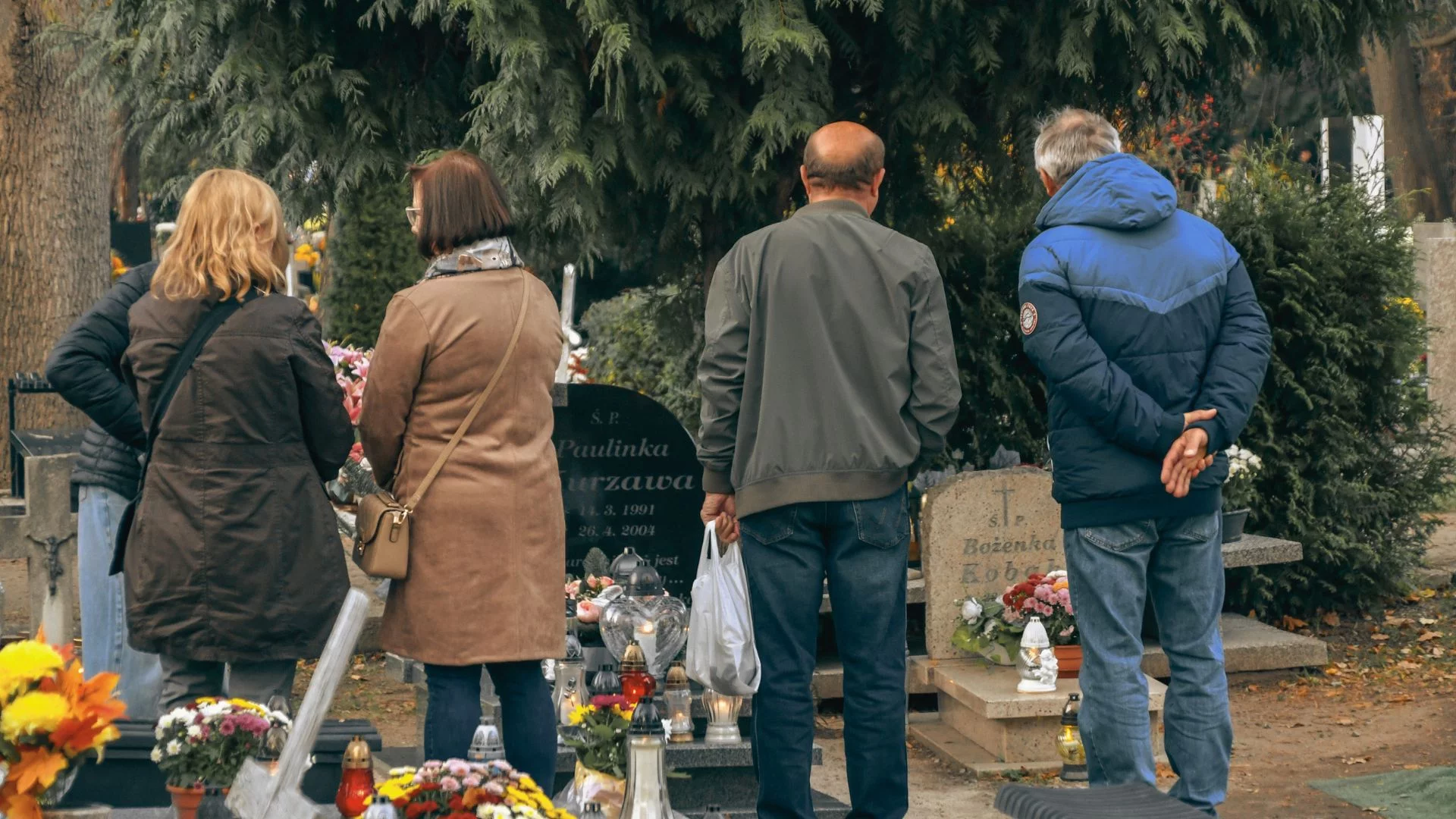 Pierwszy raz w historii urny wygrywają z trumnami. Polacy odchodzą od wieloletnich tradycji Ludzie stojący przed grobami na cmentarzu. Trumny przegrywają z urnami. Polski cmentarz nie do poznania