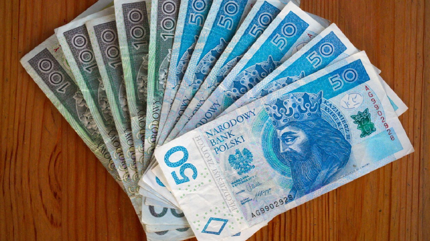 banknoty sto i pięćdziesiąt złotych leżące na drewnianym stole