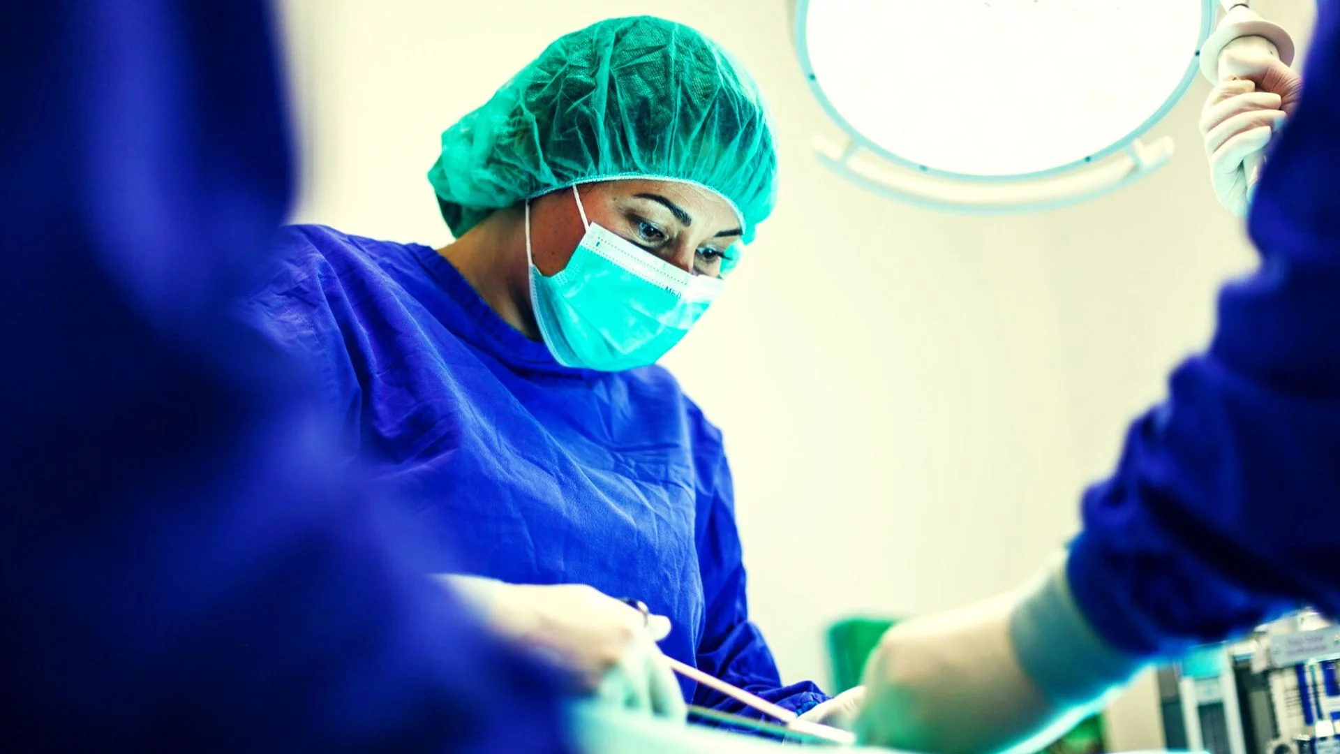 Chirurżka pochylająca się nad pacjentem na stole operacyjnym. Modelki AI i media społecznościowe nasilają dążenie do nierealnych standardów piękna.