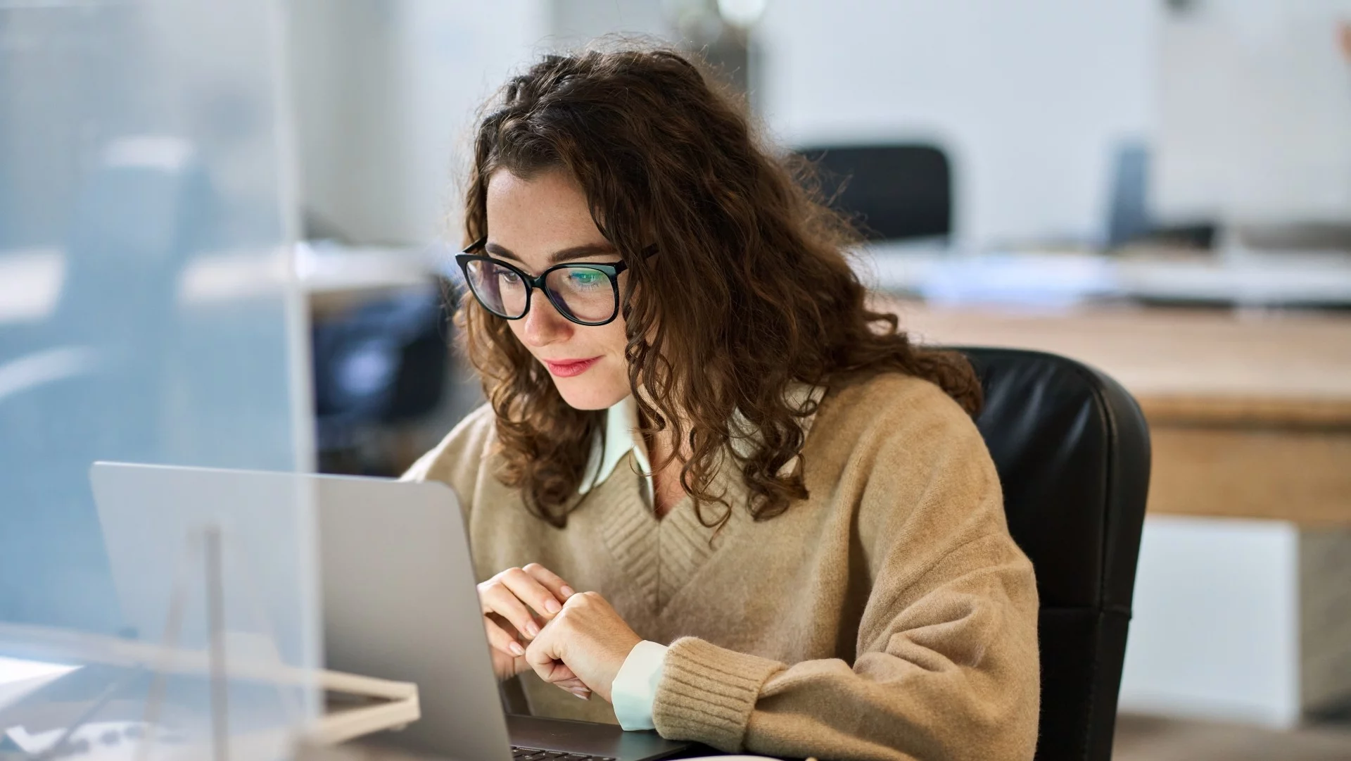 Kobieta w okularach siedząca przy biurku i pracująca przy laptopie. Polska wyprzedziła Niemcy pod względem równości płci w pracy.