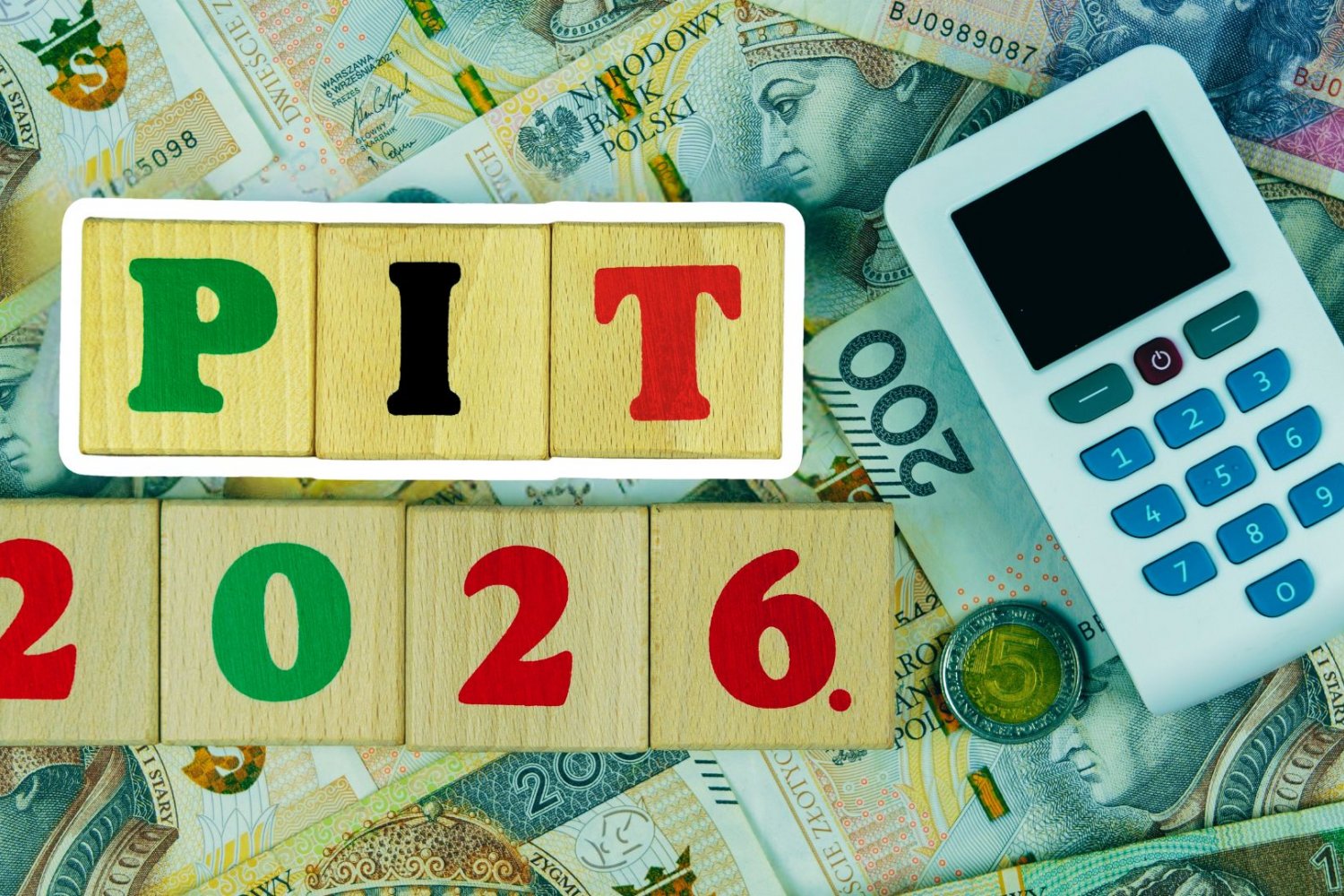 PIT 2026 z blokami drewnianymi i tokenem bankowym na banknotach złotych polskich