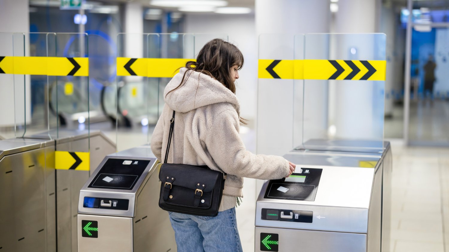 Kobieta kasująca bilet na bramkach w metrze.
