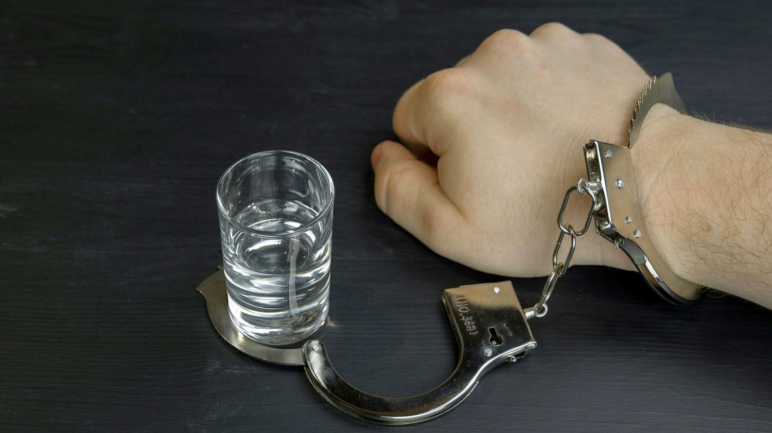 Renta alkoholowa w górę. ZUS wypłaci więcej, w narodzie rośnie wzburzenie kajdanki obejmujące z jednej strony męską rękę, z drugiej kieliszek z alkoholem